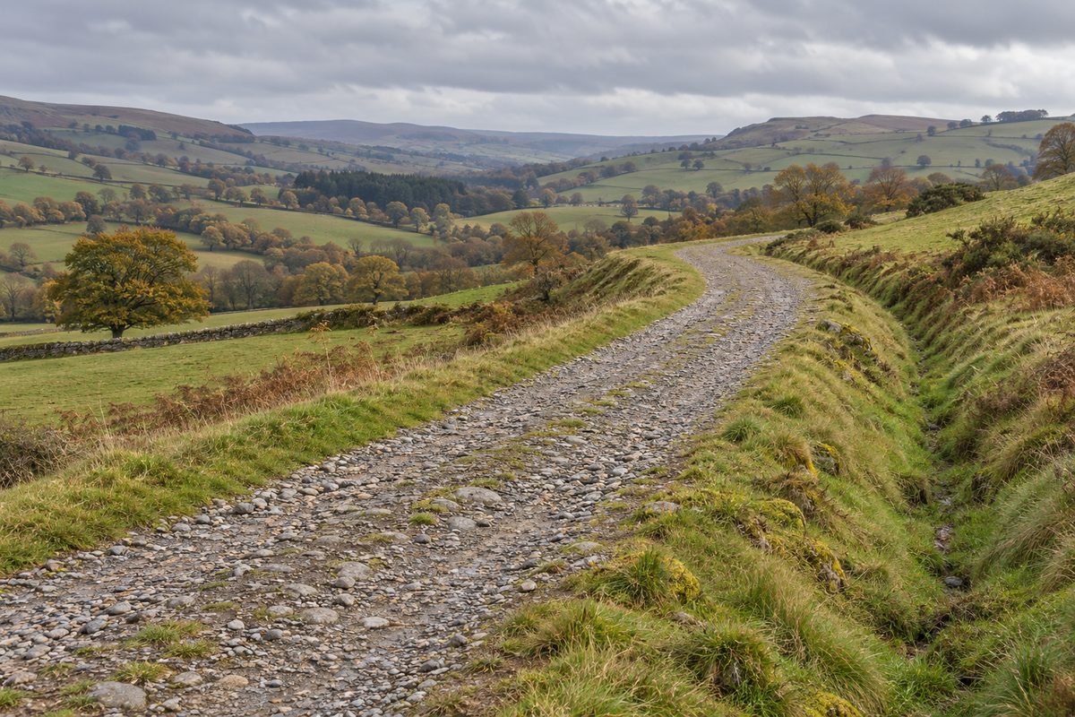 A raised stone-and-gravel track bends gently across grassy rolling countryside.